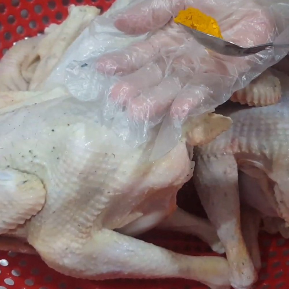 Xoa đều các gia vị và bột nghệ lên gà để gà thấm, vàng đều khi luộc